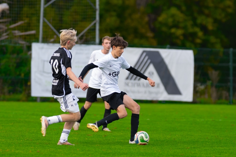 Fußballspielende Jugendliche auf einem Rasenfeld in Österreich, ein Bursche dribbelt den Ball.